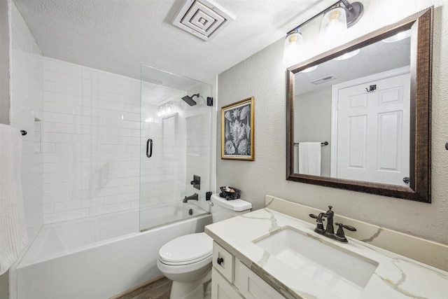 full bathroom with vanity, tiled shower / bath, hardwood / wood-style flooring, toilet, and a textured ceiling