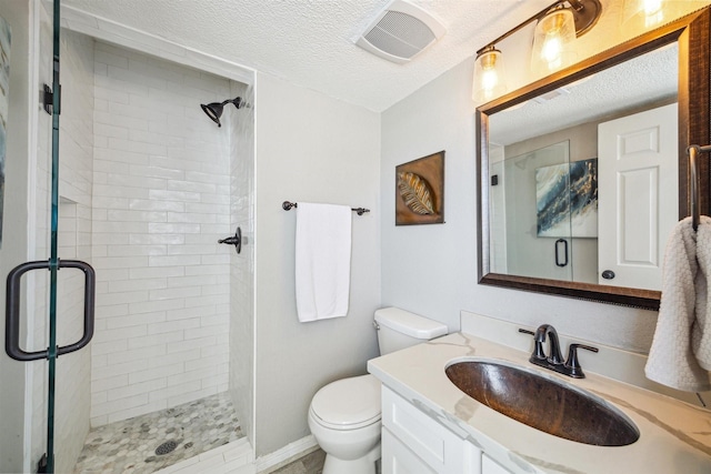 bathroom with a textured ceiling, vanity, toilet, and walk in shower