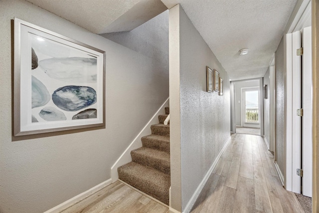 corridor featuring light hardwood / wood-style floors and a textured ceiling