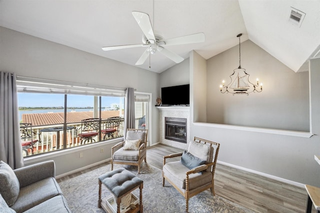 living room with hardwood / wood-style flooring, ceiling fan with notable chandelier, and vaulted ceiling