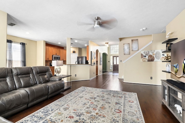 living room with ceiling fan, dark wood-type flooring, and a textured ceiling