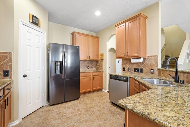 kitchen featuring sink, light tile patterned floors, tasteful backsplash, light stone counters, and stainless steel appliances