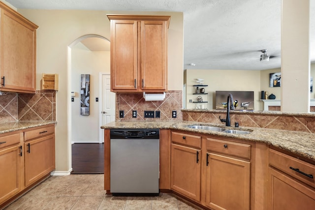 kitchen featuring decorative backsplash, light stone countertops, sink, light tile patterned floors, and dishwasher