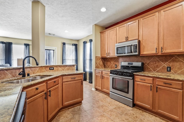 kitchen featuring backsplash, a textured ceiling, stainless steel appliances, sink, and light tile patterned floors