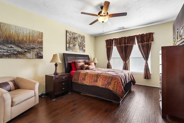 bedroom with a textured ceiling, ceiling fan, and dark wood-type flooring