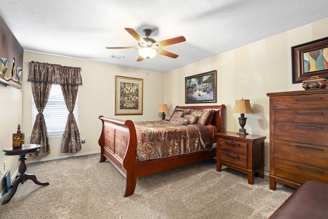 bedroom with ceiling fan, light colored carpet, and a textured ceiling