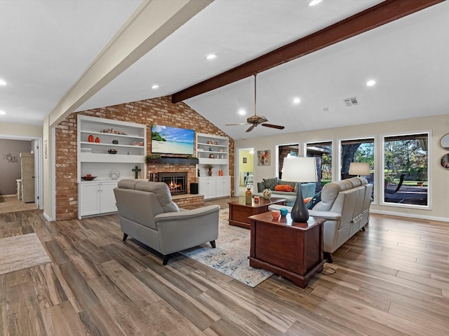 living room with a brick fireplace, vaulted ceiling with beams, built in shelves, ceiling fan, and light hardwood / wood-style floors