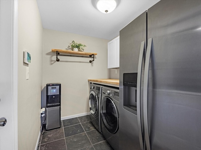 laundry room with washing machine and clothes dryer, dark tile patterned floors, and cabinets