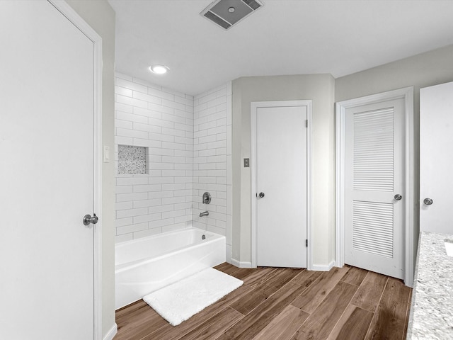 bathroom with hardwood / wood-style floors and tiled shower / bath