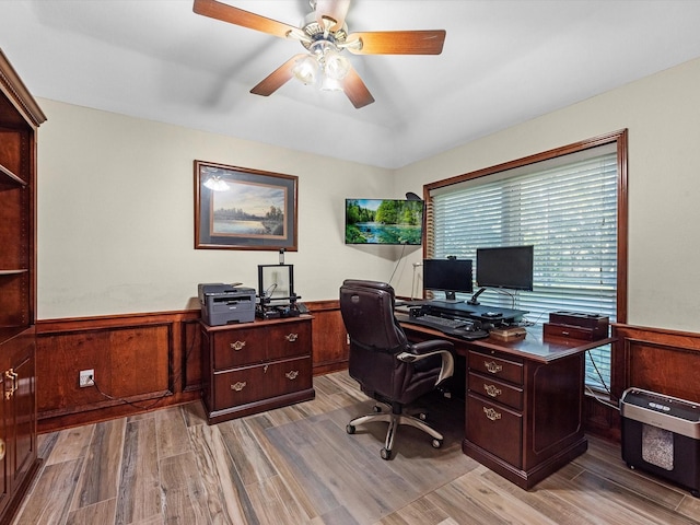 office space with ceiling fan, wooden walls, and light hardwood / wood-style flooring