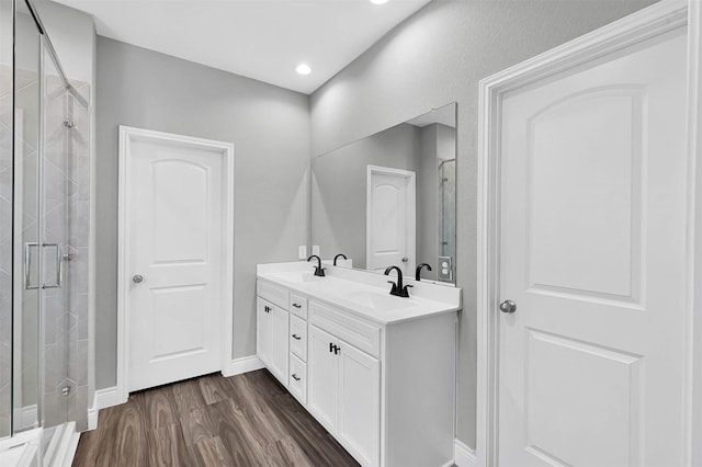 bathroom with hardwood / wood-style floors, vanity, and a shower with shower door