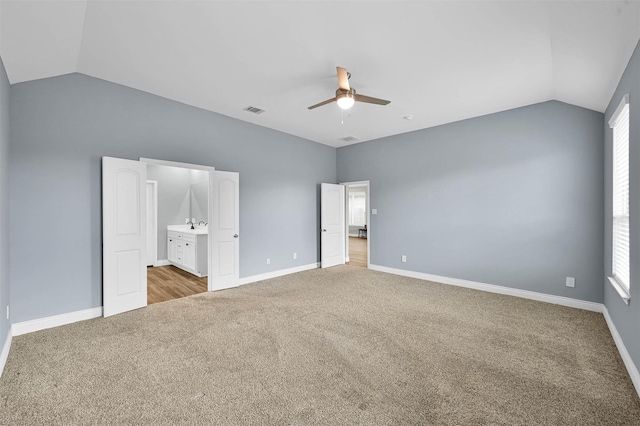 unfurnished bedroom with ensuite bathroom, ceiling fan, lofted ceiling, and light colored carpet