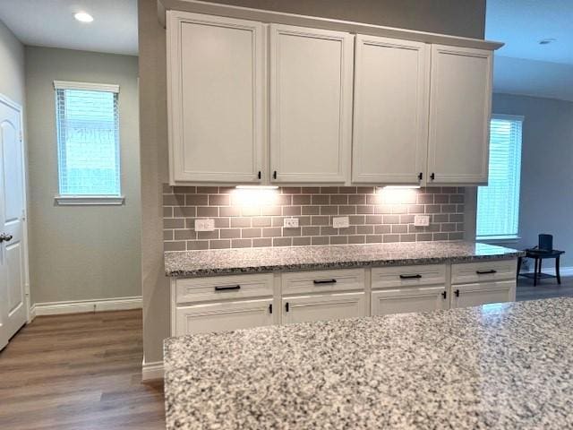 kitchen with white cabinets, light stone counters, and a wealth of natural light