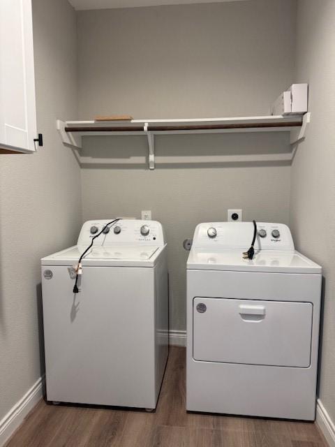 clothes washing area with cabinets, independent washer and dryer, and dark hardwood / wood-style floors