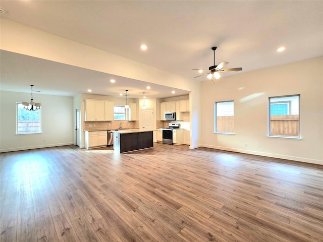 unfurnished living room with hardwood / wood-style floors, ceiling fan with notable chandelier, and sink