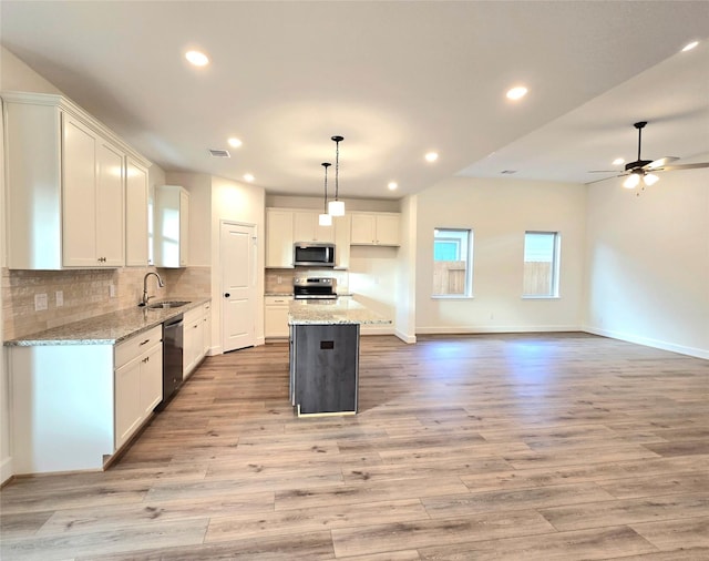 kitchen featuring white cabinetry, a center island, sink, decorative light fixtures, and appliances with stainless steel finishes