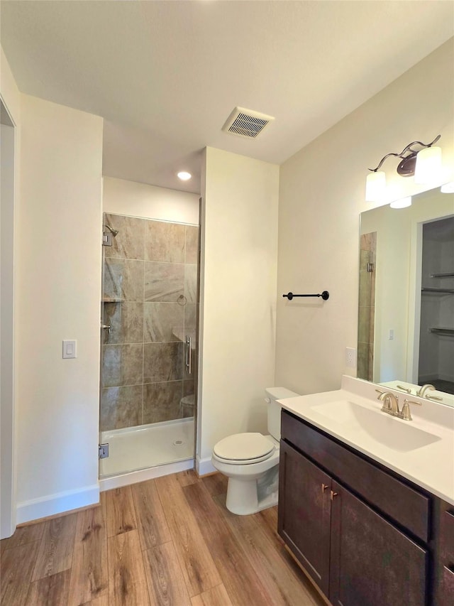 bathroom featuring a shower with door, vanity, wood-type flooring, and toilet