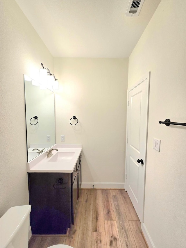 bathroom with hardwood / wood-style floors, vanity, and toilet