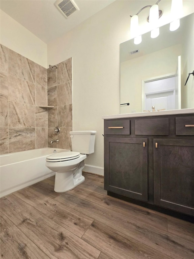 full bathroom featuring hardwood / wood-style flooring, vanity, toilet, and tiled shower / bath