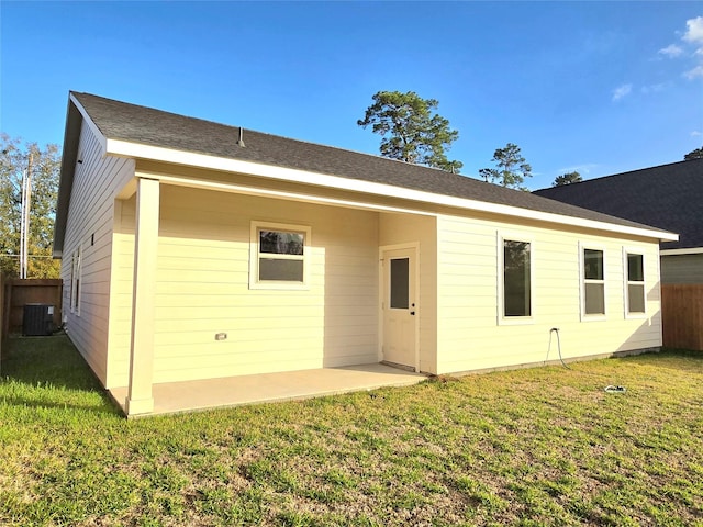 rear view of house featuring a lawn and central air condition unit