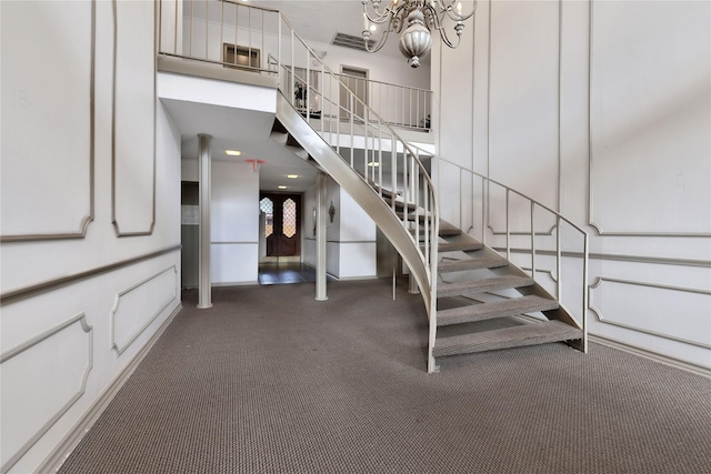 stairs with carpet floors and an inviting chandelier