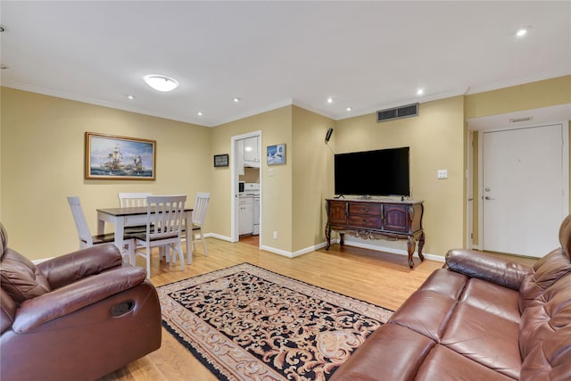 living area with light wood-style floors, visible vents, ornamental molding, and baseboards