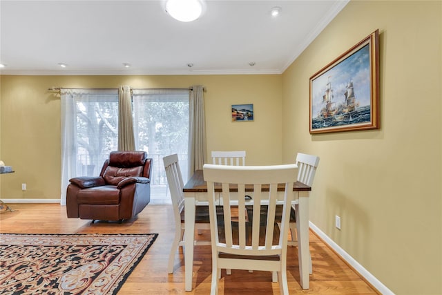 dining space featuring light wood-type flooring and crown molding