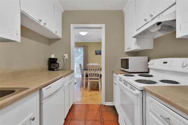 kitchen with white cabinets, white appliances, dark tile patterned flooring, and crown molding