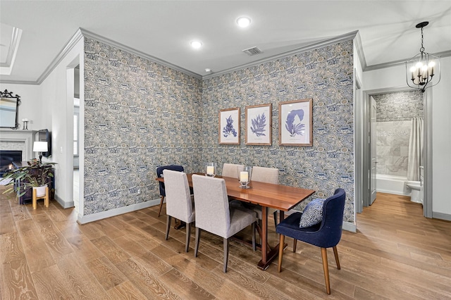 dining area with hardwood / wood-style flooring, an inviting chandelier, and ornamental molding