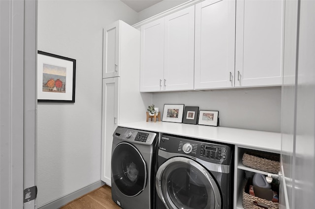 clothes washing area with cabinets, separate washer and dryer, and light hardwood / wood-style floors