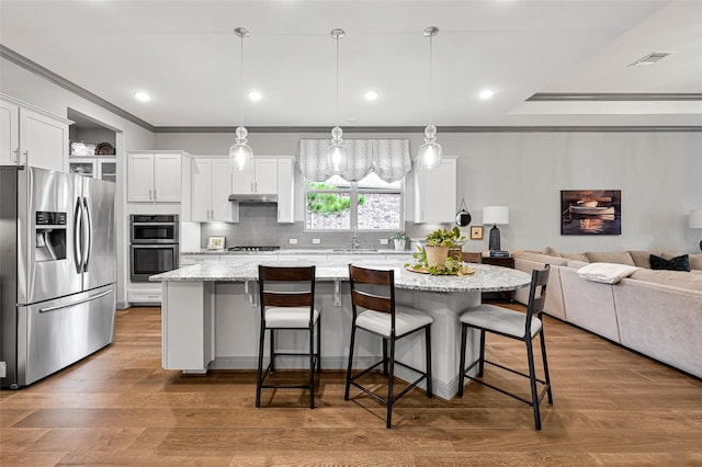 kitchen with white cabinets, stainless steel appliances, a kitchen island, and hanging light fixtures