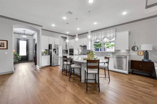 kitchen featuring a kitchen island, wood-type flooring, white cabinetry, and stainless steel appliances