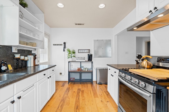 kitchen featuring backsplash, white cabinets, stainless steel stove, and light wood-type flooring