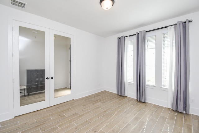 spare room with french doors and light hardwood / wood-style floors