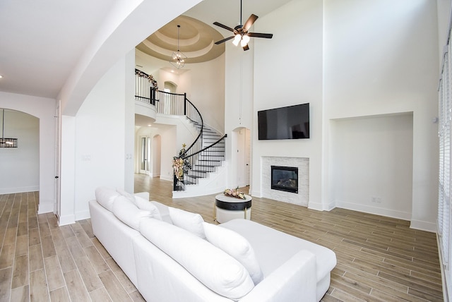 living room with ceiling fan with notable chandelier, a raised ceiling, and a towering ceiling