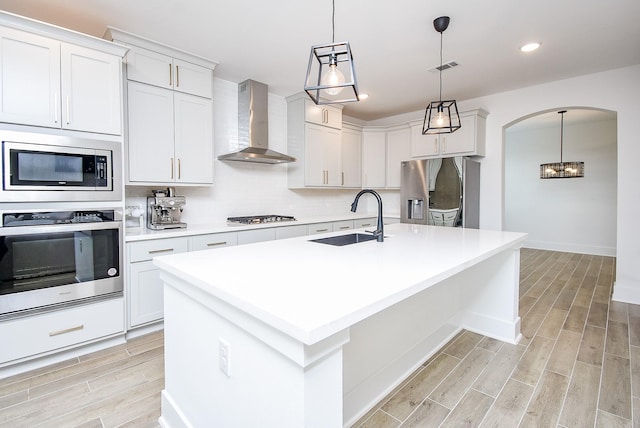 kitchen with white cabinets, sink, wall chimney range hood, and stainless steel appliances