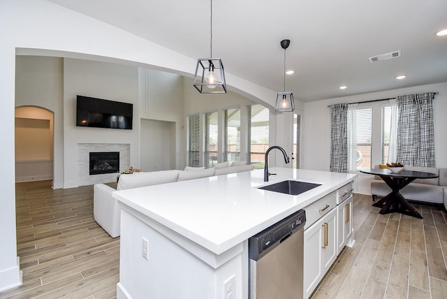 kitchen featuring white cabinetry, dishwasher, sink, an island with sink, and pendant lighting