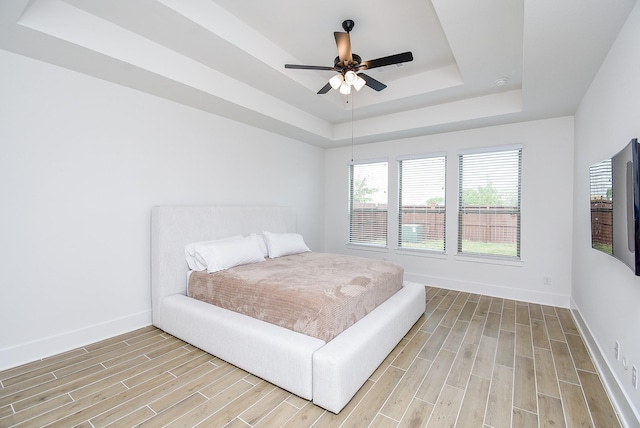 bedroom featuring a tray ceiling, ceiling fan, and light hardwood / wood-style floors