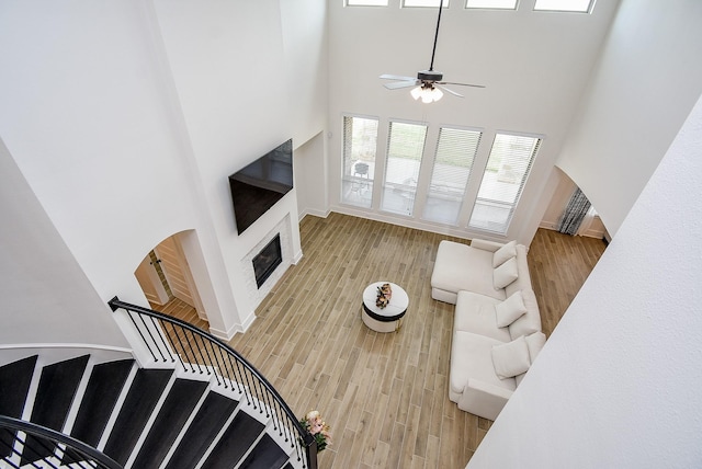 living room with ceiling fan, light hardwood / wood-style floors, and a high ceiling