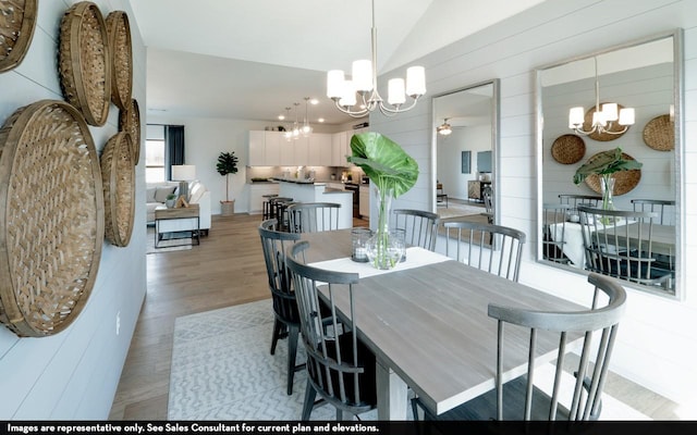 dining space with ceiling fan with notable chandelier, light wood-type flooring, and lofted ceiling