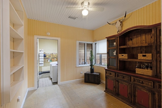 office space with built in shelves, ceiling fan, wooden walls, and washer / dryer