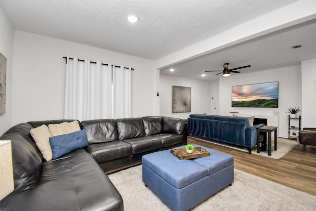 living room featuring a textured ceiling, light hardwood / wood-style floors, and ceiling fan