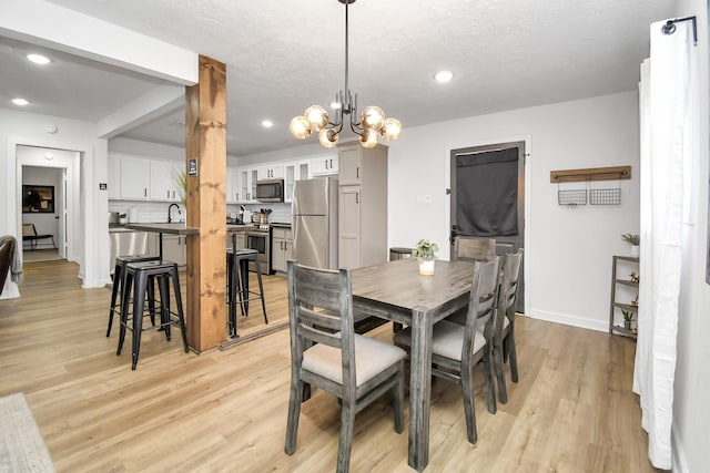 dining space with light hardwood / wood-style flooring and an inviting chandelier