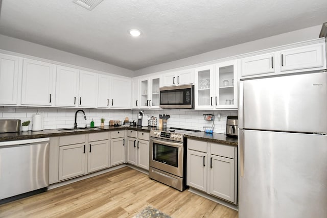 kitchen featuring sink, stainless steel appliances, backsplash, light hardwood / wood-style floors, and white cabinets