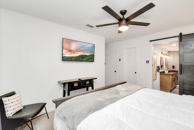 carpeted bedroom with a barn door and ceiling fan