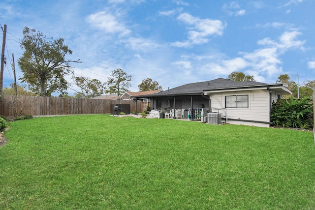 rear view of house with a lawn, a sunroom, and central AC unit