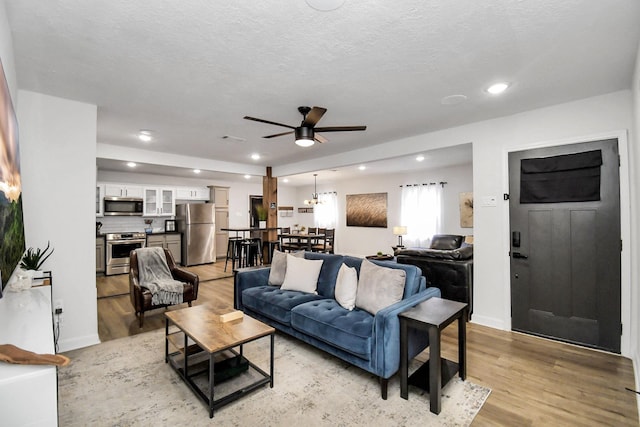 living room featuring a textured ceiling, light hardwood / wood-style floors, and ceiling fan