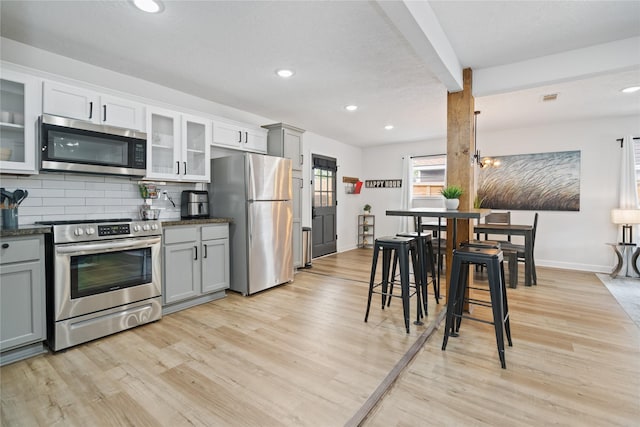 kitchen featuring stainless steel appliances, gray cabinets, tasteful backsplash, and light hardwood / wood-style floors