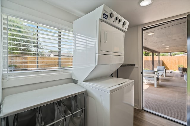 laundry area with dark wood-type flooring and stacked washer / drying machine