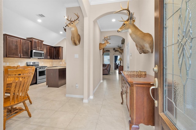 kitchen featuring a center island, light tile patterned floors, lofted ceiling, and appliances with stainless steel finishes